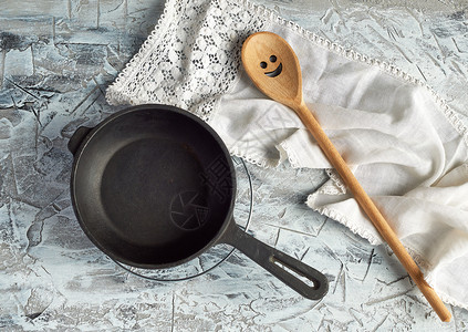 在水泥背景顶视图上摆放手柄和勺子的黑圆煎锅图片