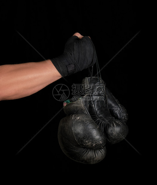 男用黑色弹运动绷带包着男手臂有两对旧式的皮衣拳击手套黑色背景复制空间图片