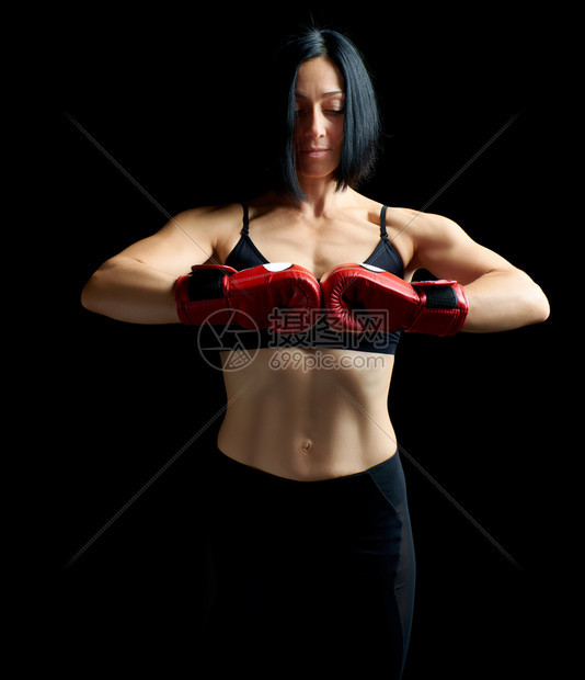 穿着黑色胸罩和腿部站在黑暗背景上双手戴着红色拳击套图片