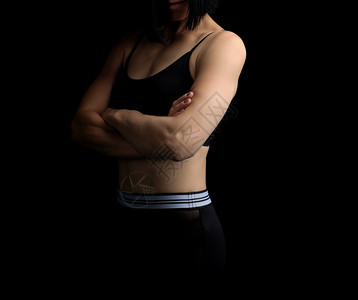 穿着黑色胸罩和腿部运动员站在侧低键背景图片