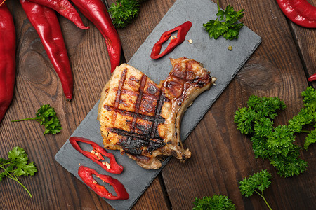肋骨上的猪肉炸牛排躺在黑板上旁边是新鲜红辣椒图片