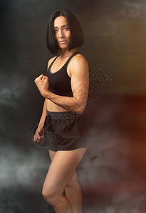 成年女孩运动数字为黑色胸罩和短裤的成年女孩站在黑暗背景肌肉身体黑头发上图片