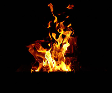 在黑暗背景的夜晚用木头和大橙色火焰燃烧的营图片