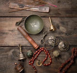 铜碗祈祷珠鼓和其他藏族宗教用具于在棕色木制背景下进行默思和替代药物图片