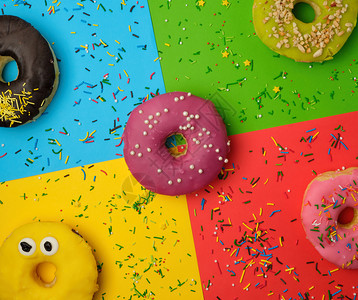 圆甜圈有各种填料和喷洒以抽象的颜色背景和节日装饰品为依托图片