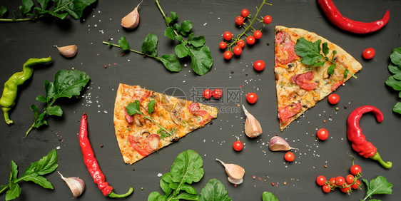 烤披萨三角饼蘑菇香肠番茄和奶酪黑色背景平铺图片