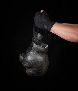 男用黑色弹运动绷带包着男手臂上面有一对旧式的皮拳击手套黑色背景图片