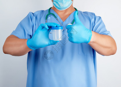 穿蓝制服的医生和穿蓝制服的乳胶手套左举着势戴一个空塑料容器用于抽取尿液样本图片