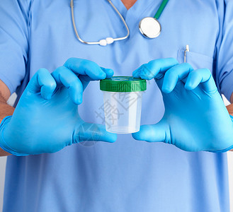 蓝色制服和乳胶手套的医生携带一个空塑料容器用于取尿液样本及时诊断的概念图片