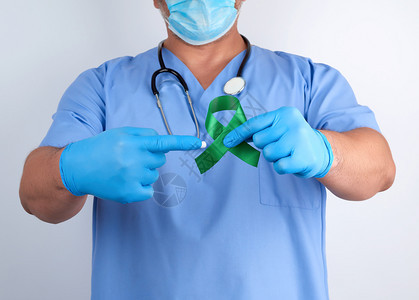 蓝制服和乳胶手套医生戴绿丝带作为早期研究和疾病控制莱姆肾移植和器官捐赠的象征图片