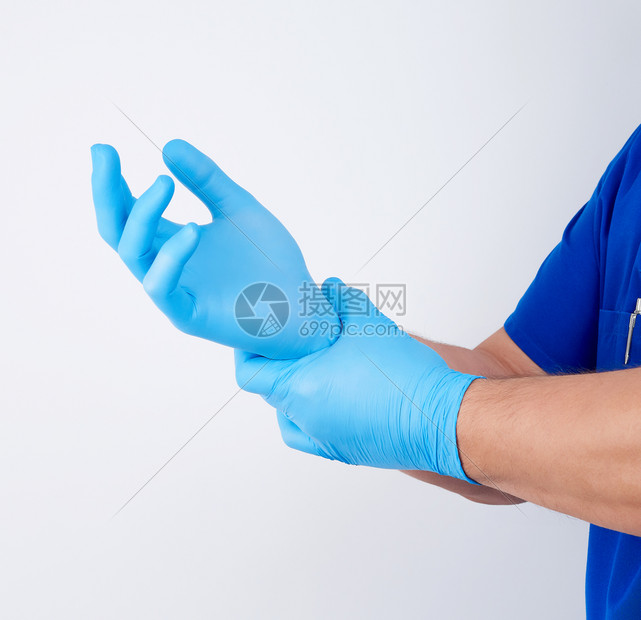穿蓝制服的男医生在手术前戴上白无菌乳胶手套白色背景图片