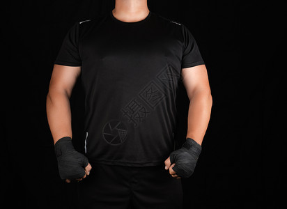身穿黑色制服的成年人运动员站在一个肌肉紧张的架子上双手被黑色的纺织绷带深底包裹在黑色的纺织绷带中图片