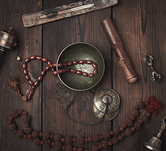 铜碗祈祷珠鼓和其他藏族宗教用具于在棕色木制背景下进行默思和替代药物图片