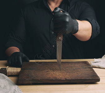黑衬衫主厨和乳胶手套拿着一把大刀用于切肉低键图片