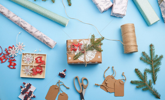 粉红色包装纸饰品采样枝圣诞玩具和带礼物的盒子放在蓝色背景顶级视图上图片
