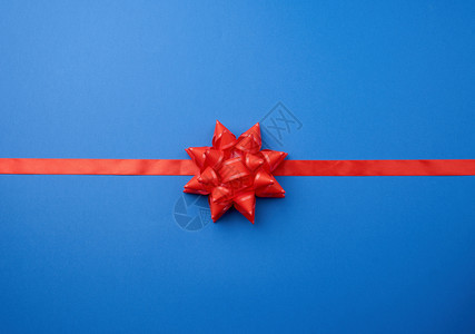 蓝色背景的红丝带和大结的弓仿礼品包装喜剧创作背景图片