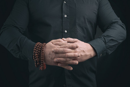 穿黑衬衫的男子在胸衣前穿过他的双臂做泥巴冥想图片