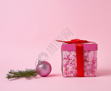 粉红色礼物盒有弓绿树枝和粉红色背景上装饰的粉红色球图片