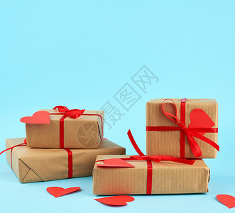 包成堆的礼物印在棕色的Kraft纸上与蓝色背景的红丝带绑在一起惊喜和情人节礼物2月14日图片