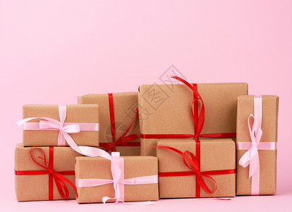 包装在着棕色克拉夫纸的盒子中并用粉红背景的丝带捆绑在粉红色背景上图片