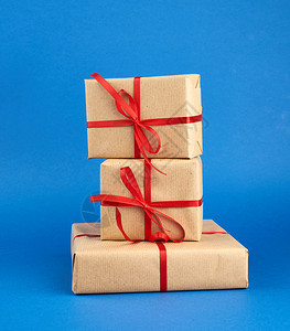 包着棕色纸和红弓的箱子蓝色背景的礼物任何用途的设计都很好假日背景情人节礼物图片