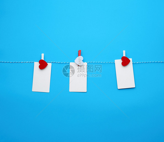 白纸长方形名卡印在装饰式衣物上红心挂在绳子上蓝色背景作刻字的地方图片