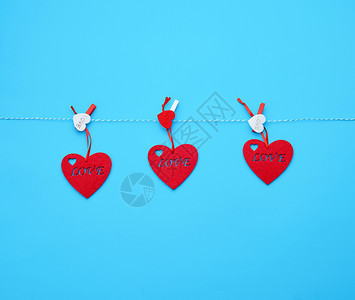 三颗红色的心挂在白绳子上紧绑着蓝色的衣帽图片