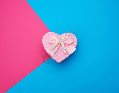 粉红礼物盒以心脏的形式蓝底顶视图喜庆背景的弓形心图片