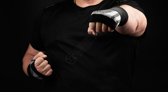 身穿黑色制服和肌肉手臂的男子站在运动姿势上双手挂着运动弹绷带底黑手部有运动弹绷带图片