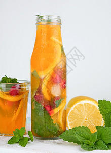 柠檬汁加红莓薄荷叶玻璃瓶中的石灰旁边是鸡尾酒的配料图片