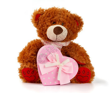 棕色的泰迪熊坐着拿一个带礼物的粉红色纸板盒白背景的玩具被孤立图片