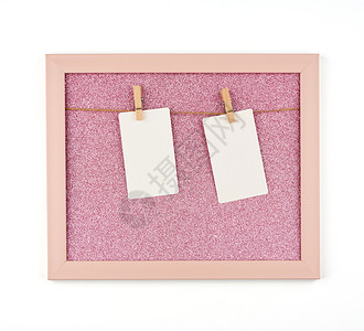 挂在木制衣物照相和刻画地点的粉红闪光板上面挂有绳子和空白纸板图片