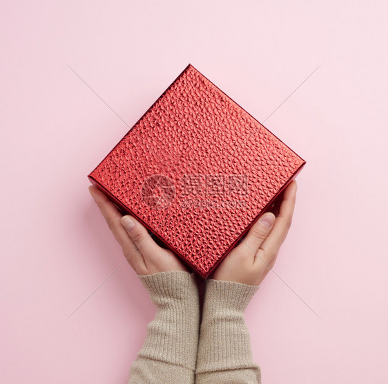 女手握红色盒子祝贺和礼物的概念最高视野粉红背景图片