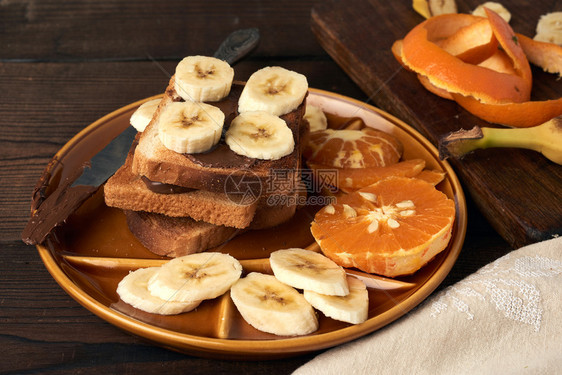 烤三明治加巧克力糊和香蕉片在盘子上早餐关门图片