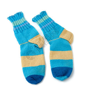 由羊毛蓝衣和白色背景隔绝的蓝衣服制成两对条纹状手工编织的暖袜子背景图片