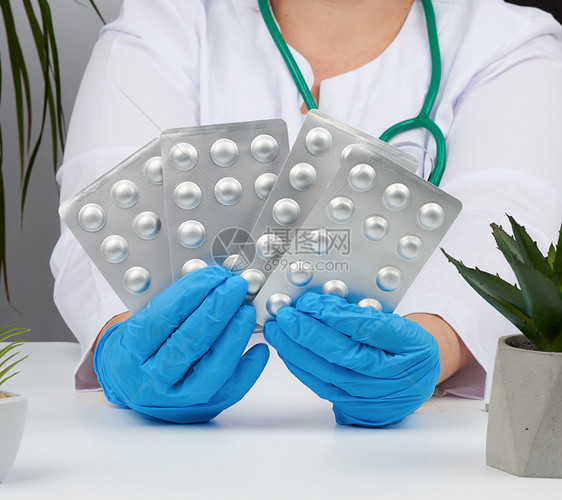 女用蓝色消毒手套在浴缸里装着一堆药丸关于物治疗疾病的概念医生坐在桌子和办公室的扶椅上图片