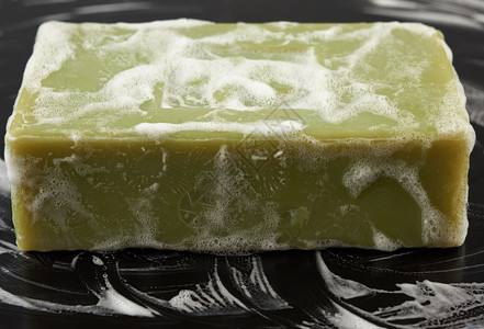 天然绿色肥皂和黑背景白泡沫的天然绿色肥皂卫生概念封闭图片