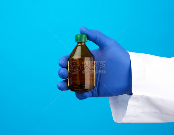 医疗手套装着棕色玻璃瓶用于蓝底药品图片