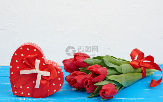 红色盛开的郁金香花束配有绿色叶子蓝木背景的包装礼物生日情人节周年纪念的日背景图片