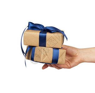 手握着一堆包的礼物装在棕色手纸上绑着丝弓对象在白色背景上隔离图片