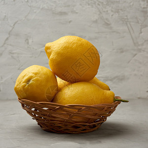 在灰色桌边的圆篮子里成熟的黄柠檬水的成分图片