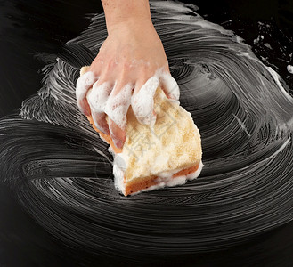 白色肥皂泡沫中的女手握着湿海绵擦黑表面清洁和洗涤表面的概念最高视线图片
