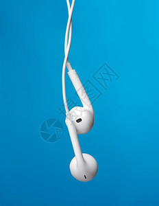 白色电缆上挂着耳机蓝色背景上的现代小工具关上图片