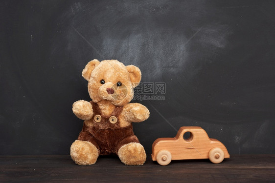 棕褐色泰迪熊坐在棕木制桌和汽车上坐在空黑粉笔板后面一个作碑文的地方回到学校图片