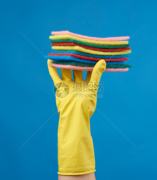 将清洗用的黄色橡胶手套放在他的上,将部分举起来,并用蓝底布置着一堆厨房用海绵图片