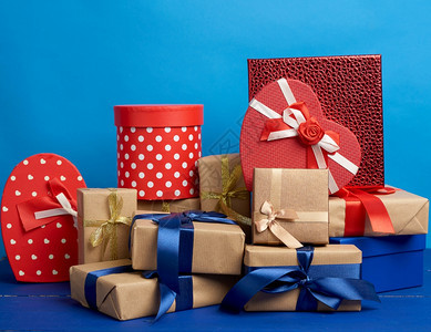 包在着棕褐色克拉夫纸的盒装礼物中并绑在蓝色背景的丝带生日节圣诞的喜庆背景图片