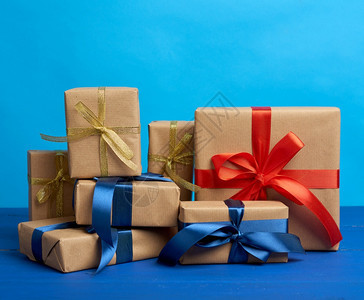 包在着棕褐色克拉夫纸的盒装礼物中并绑在蓝色背景的丝带生日节圣诞的喜庆背景图片