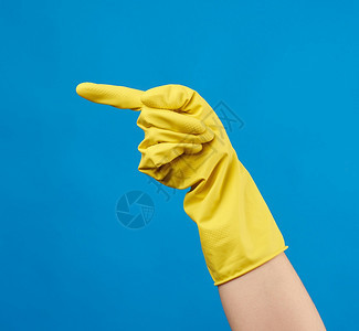 黄色橡胶手套用于清洗身着女手蓝底被抬起的部分身体图片
