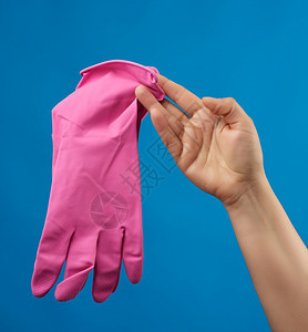 女手持粉色橡皮套用于清洁蓝底保护衣服用于家庭清洁图片