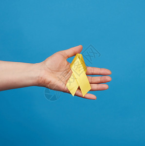 女性手上握着黄丝带,以蓝底环绕的方式,象征着与猫肿瘤的斗争,及其预防问题图片
